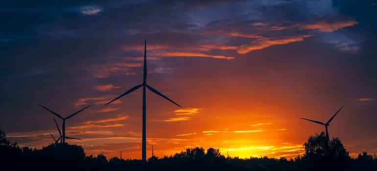 A silhouette of windturbines on a amazing sunset
