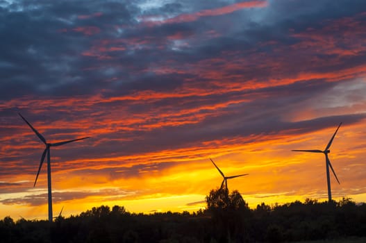A silhouette of windturbines on a amazing sunset