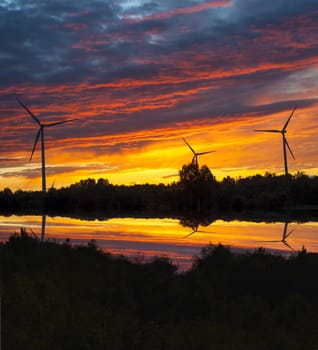 A silhouette of windturbines on a amazing sunset