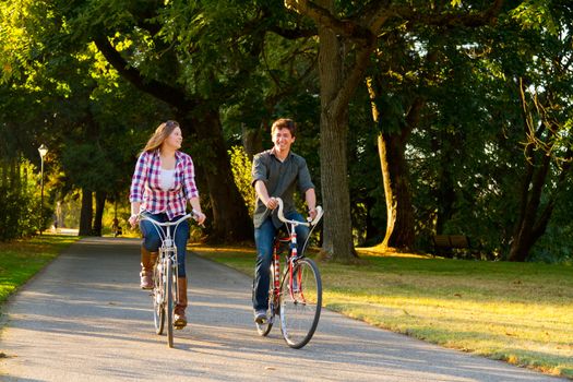 A man and a woman with their bicycles on a bike path in an outdoor park setting.