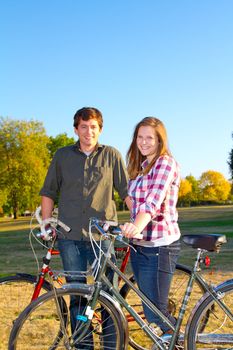 A couple poses for this portrait in a field with their bicycles.