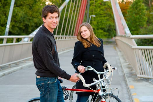 A married man and woman with their bikes on a bicycle path bridge.