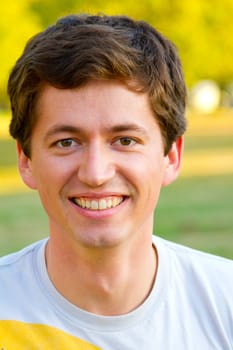 A portrait of an attractive man outdoors in a park setting.