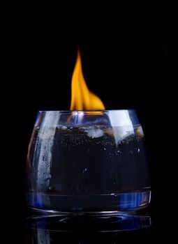 cola with cognac and fire in glass on black