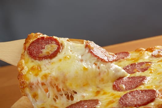 homemade pizza  Pepperoni .taking slice of pizza,melted cheese dripping.