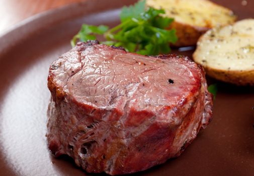 Grilled beef on white plate with potatoes salad and tomatoes  .closeup