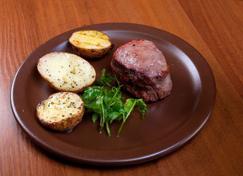 Grilled beef on white plate with potatoes salad and tomatoes  .closeup