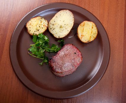 Grilled beef on white plate with potatoes salad and tomatoes  .closeup