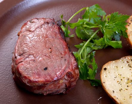 Grilled beef on white plate with potatoes salad and tomatoes  .Shallow depth-of-field. 