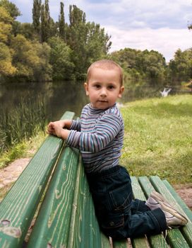 boy sits on a park bench in the open air