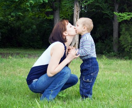 Mother kissing baby outdoors in the park