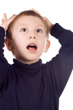 Portrait of surprised little boy with blond hair covering his mouth by hands