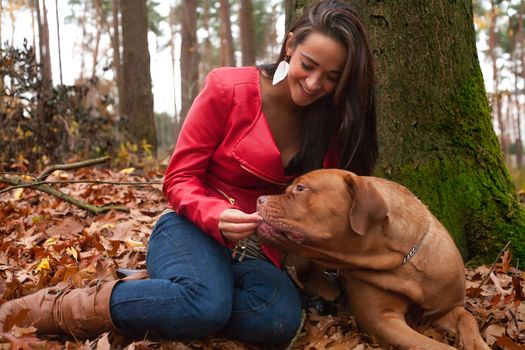 Young woman is having fun with her dog in the forest