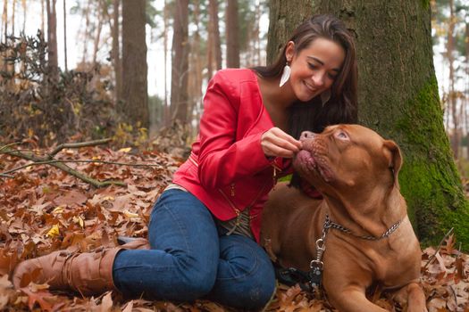 Young woman is having fun with her dog in the forest