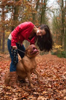 Young woman is having fun with her dog in the forest