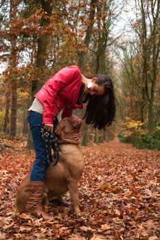 Young woman is having fun with her dog in the forest