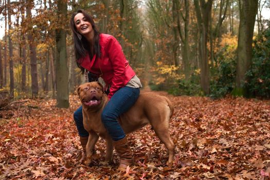 Young woman is having fun with her dog in the forest