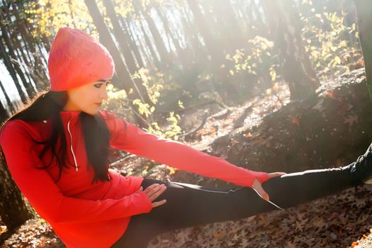 Young woman is working on her body in the forest