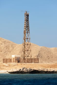 Sea Lighthouse on stony bare mountain under a clear blue sky