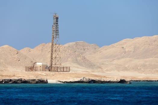 Sea Lighthouse on stony bare mountain under a clear blue sky