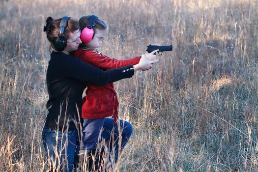 Mother teaching her young daughter how to safely and correctly use a handgun.