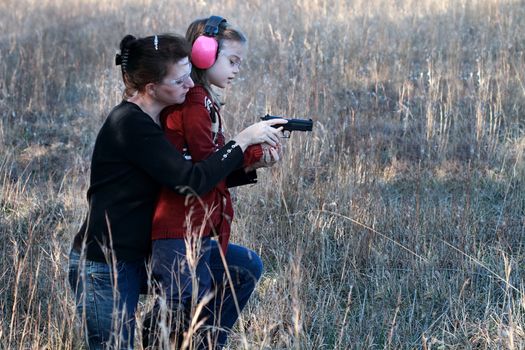 Mother teaching her young daughter how to safely and correctly use a handgun.
