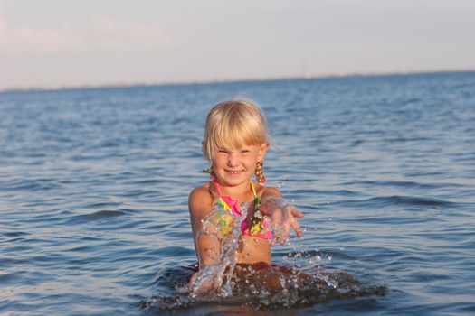 happy girl splashing in water at the evening