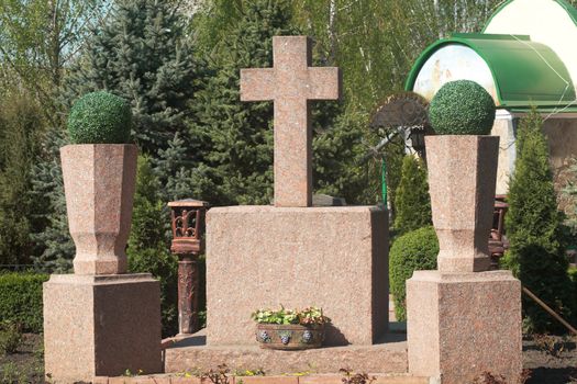 Stone cross on a cemetery. Tomb near church