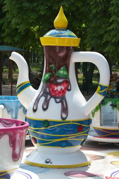 Jug and cup in park. Cheerful merry-go-round