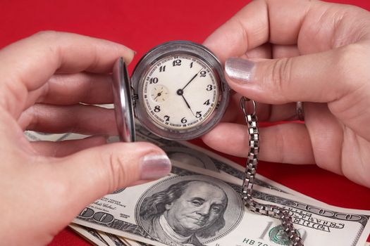Watch and dollars on a red table. Businesswoman