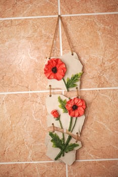 Red artificial flowers hang on a wall. An interior in a room