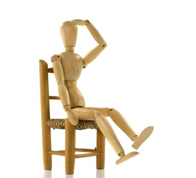 wooden puppet on chair staring and thinking