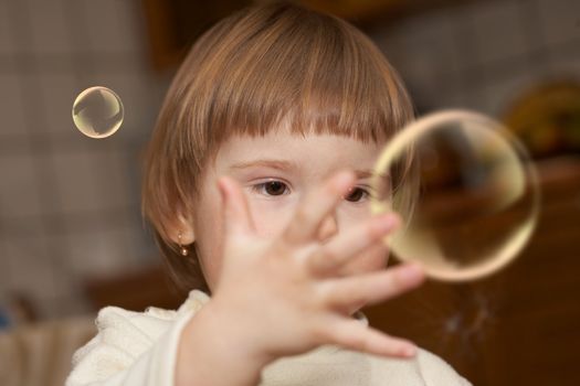 The small girl plays with soap bubbles. Childhood