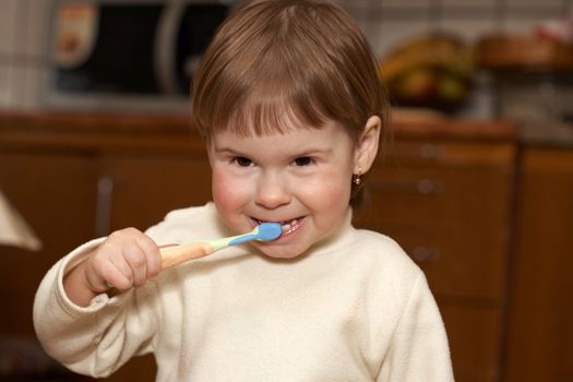 The small girl cleans teeth in a room. Hygiene