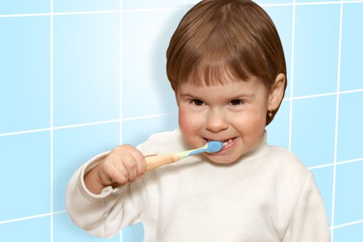 The small girl cleans teeth in a blue bathroom