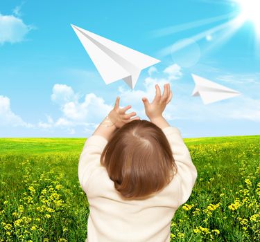 The small girl plays with the paper airplane. Nature