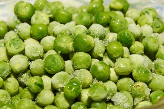 Green peas covered by ice crystals close-up