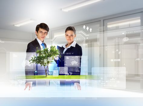 young businesspeople looking at high-tech image of tree