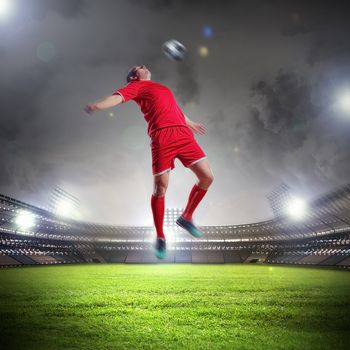 football player in red shirt striking the ball at the stadium