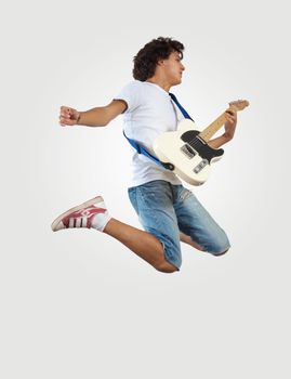 young man playing on electro guitar and jumping