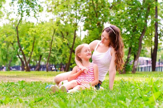 mother and daughter sitting together on the grass, and spend time with family