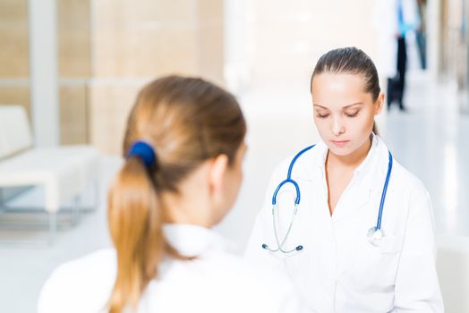 two doctors talking in the lobby of the hospital, sitting on the couch