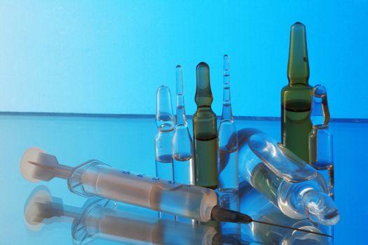 Medicine. Ampoules and syringe on a blue background