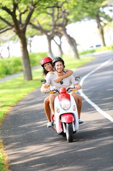 Scooter - couple driving in summer having fun on vacation holidays. Young happy interracial couple driving scooter. Asian woman, Caucasian man.