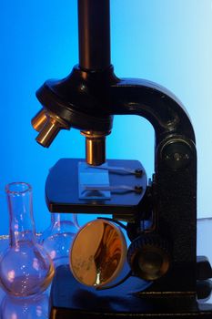 Microscope and laboratory glasswares on a blue background