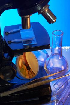 Microscope and laboratory glasswares on a blue background