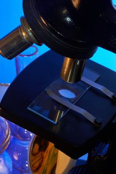 Microscope and laboratory glasswares on a blue background