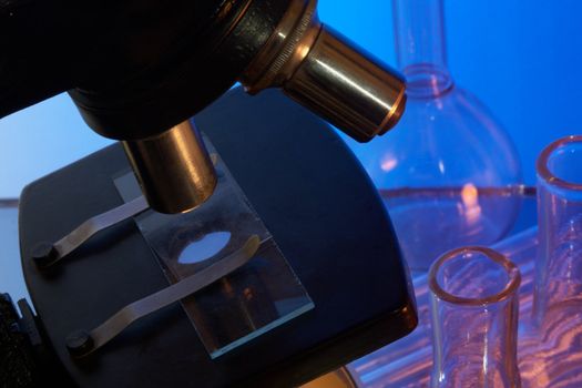 Microscope and laboratory glasswares on a blue background