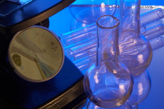 Microscope and laboratory glasswares on a blue background