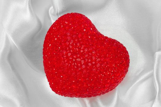 Red heart on white silk textured background